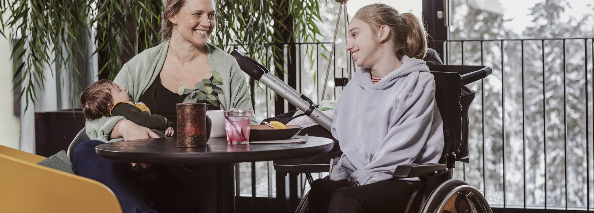 En kvinna är på ett café tillsammans med en yngre flicka som använder rullstol   