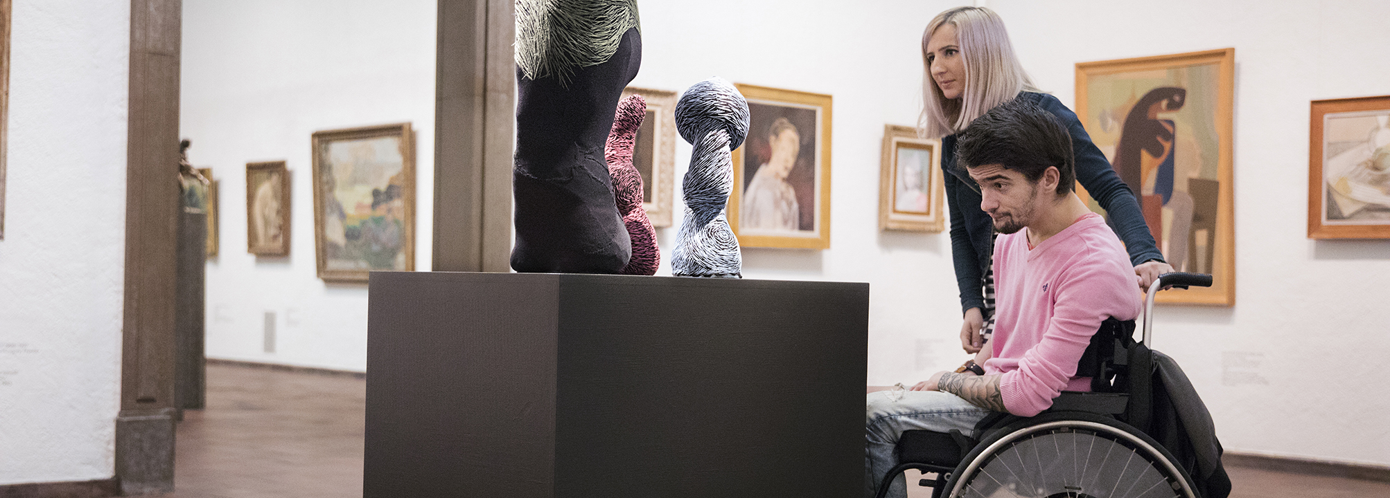 Person i rullstol tittar på konst i ett museum.