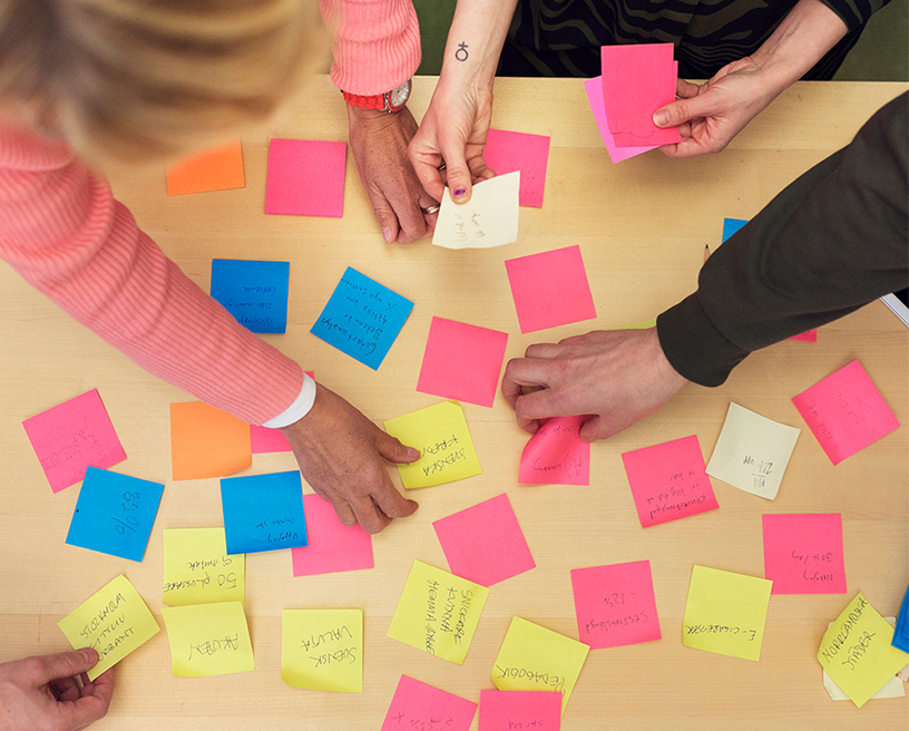 Fyra personer sorterar postitlappar som ligger på ett bort. 