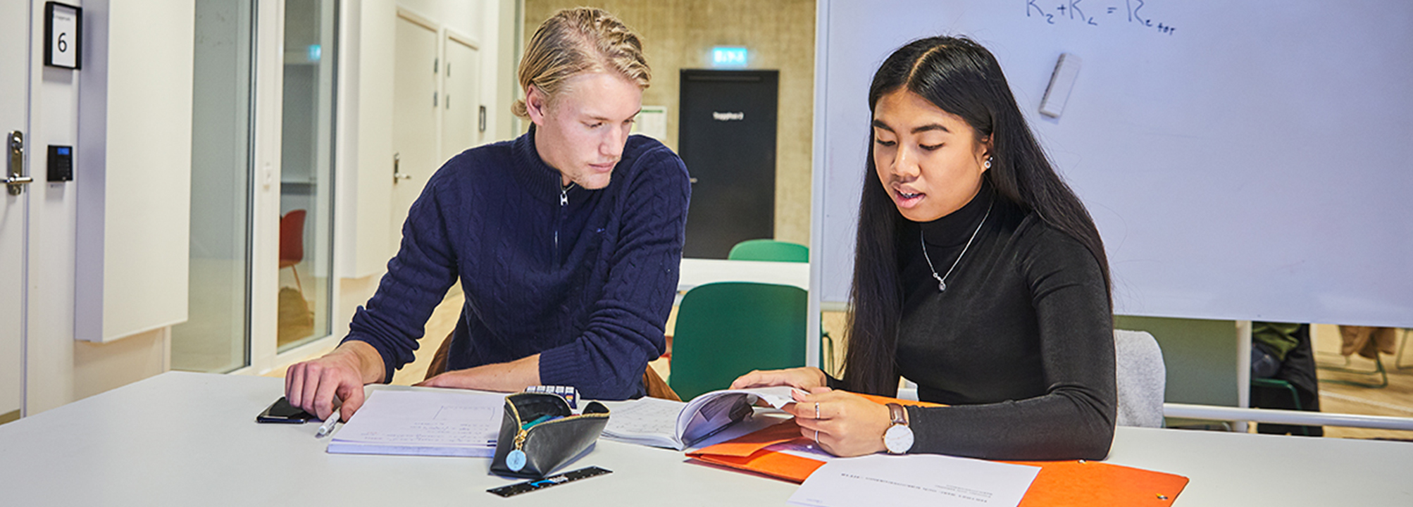 Två gymnasieelever i klassrum.