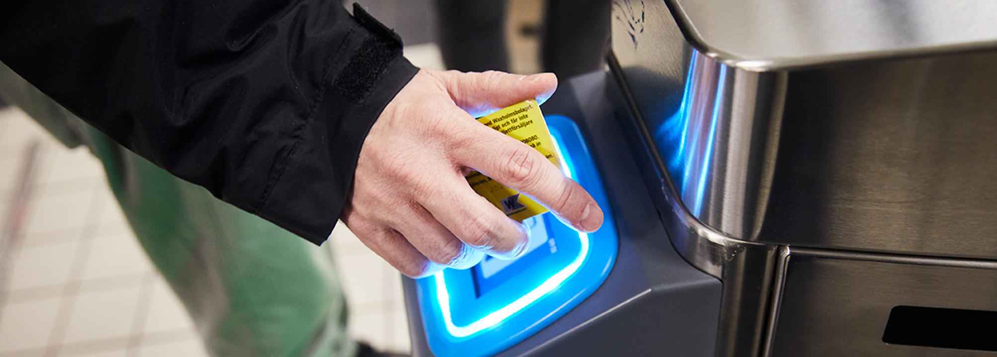 En personer som går igenom biljettkontrollen på en station. 
