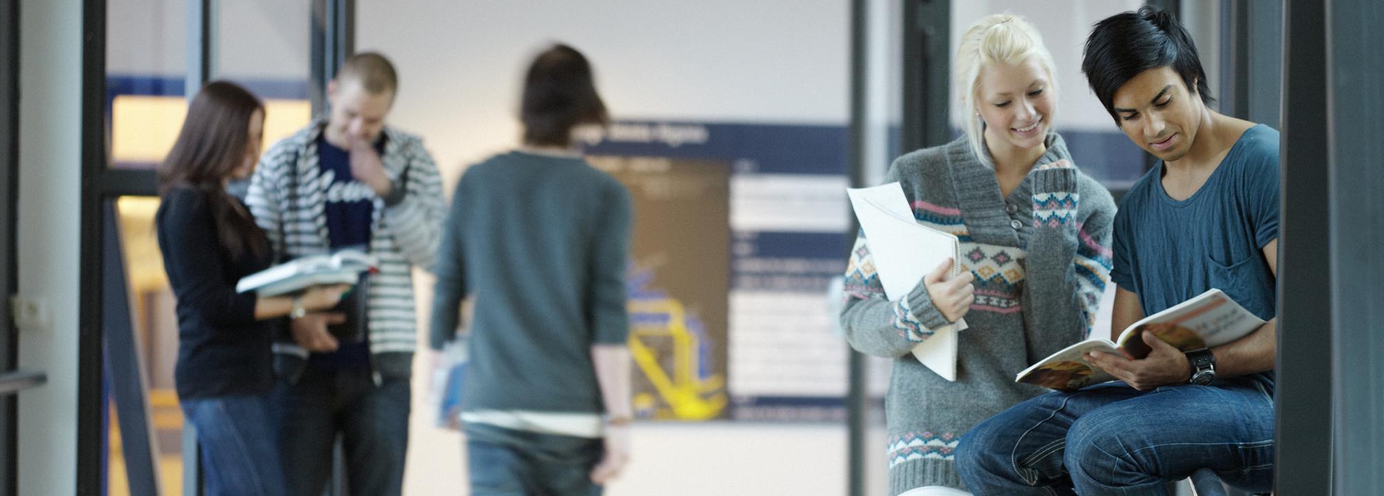 En tonårig pojke och flicka är i en skolkorridor och tittar i ett studiematerial