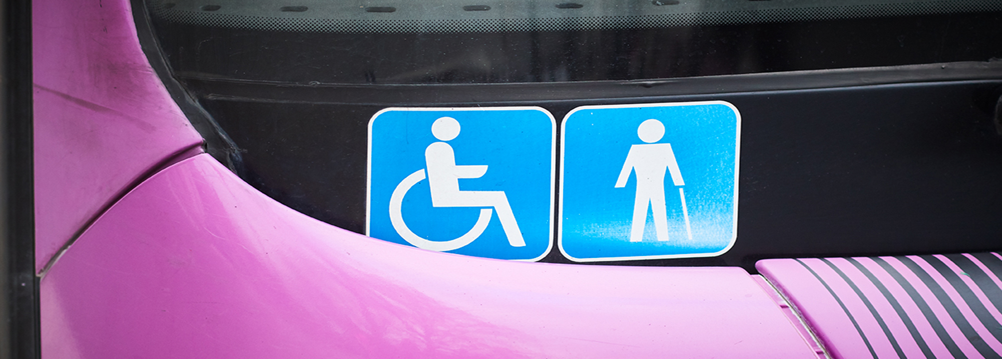 Två funktionsnedsättningsskyltar i fönstret på en buss.