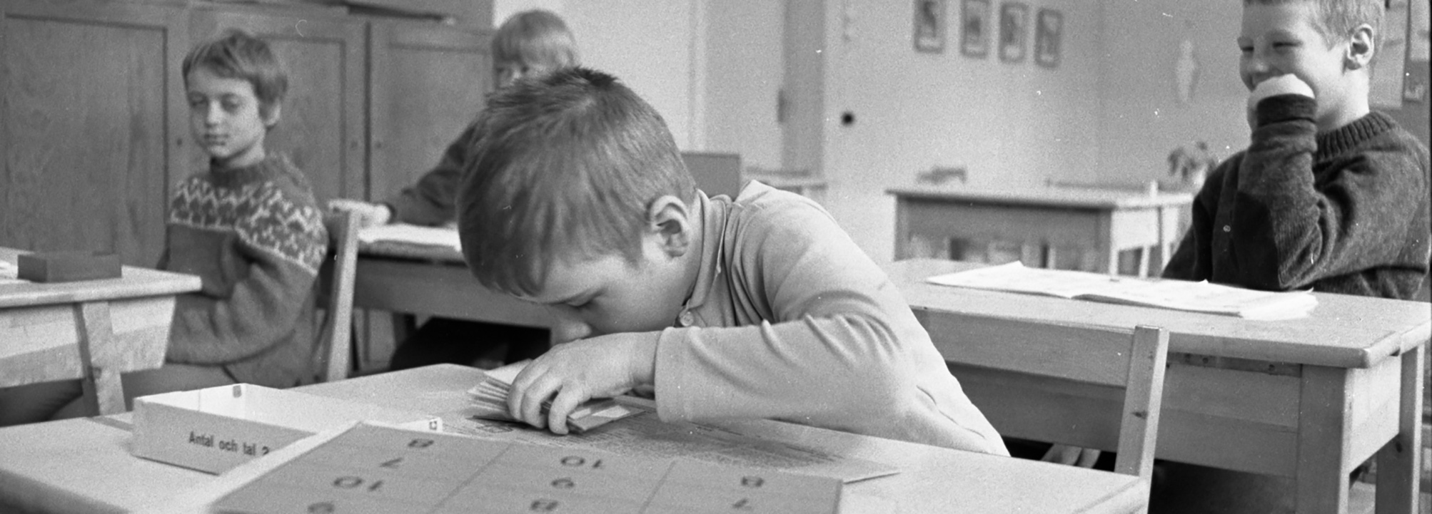  Ett antal barn, pojkar och flickor, i en skolsal som arbetar med skoluppgifter