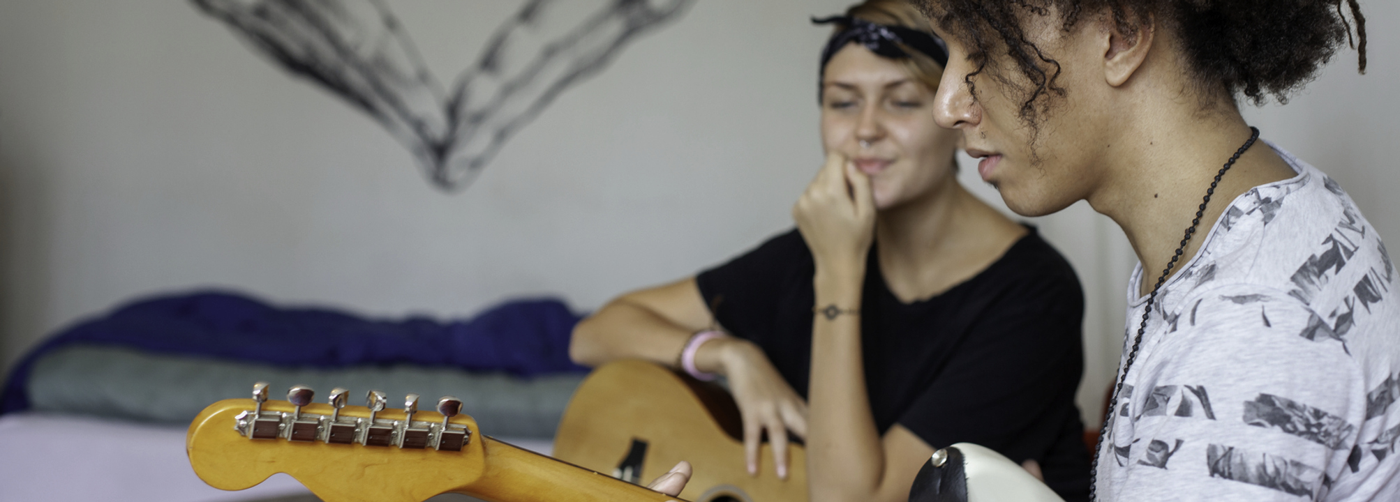 Två tonåringar spelar gitarr i ett sovrum.