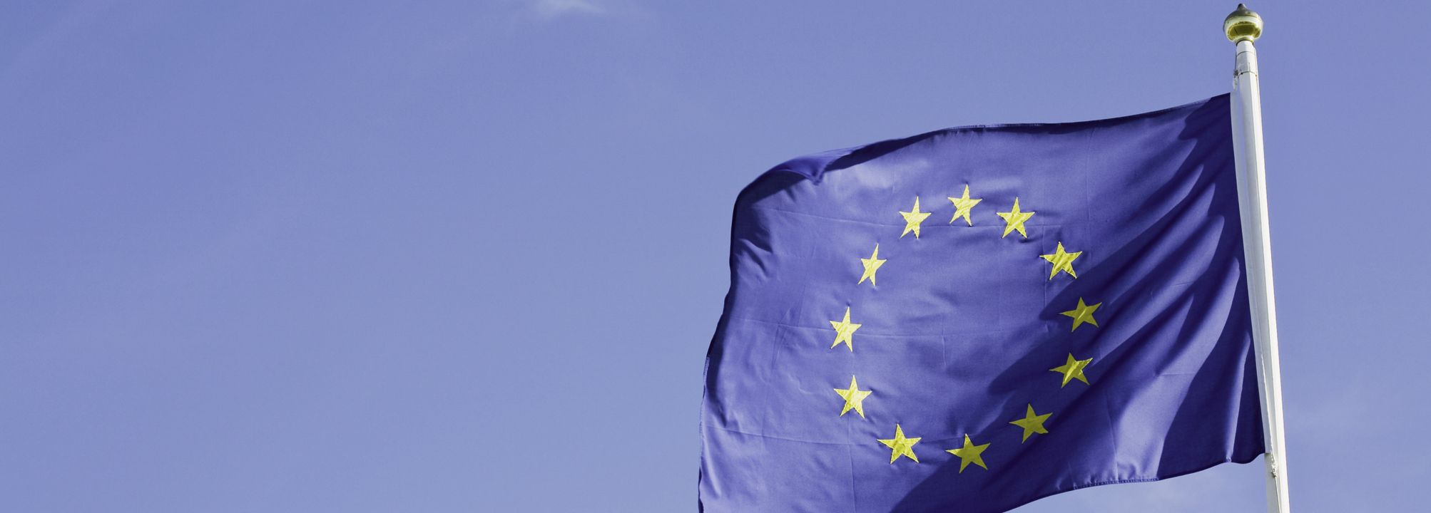 EU-flagga vajar mot blå himmel.