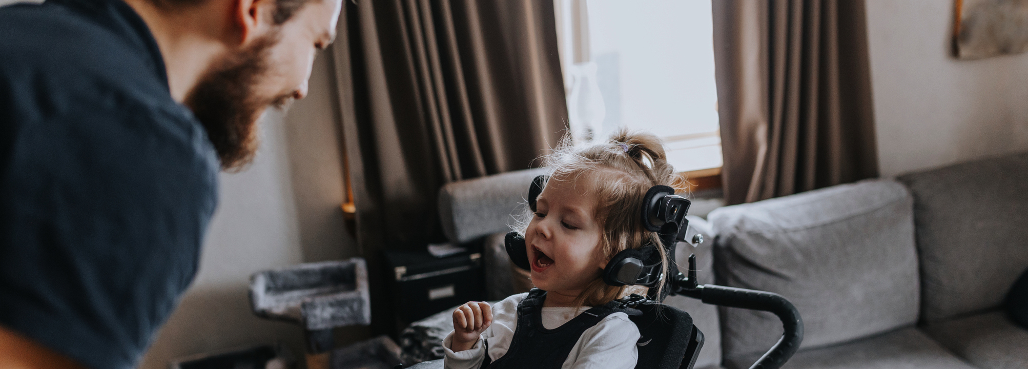 En man som står framför en liten flicka i permobil