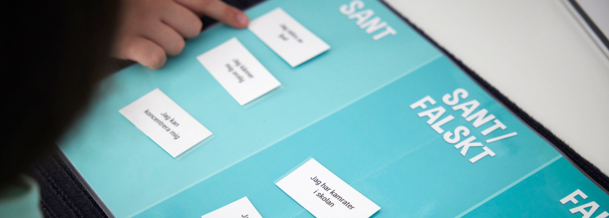 Barn på habiliteringsavdelning svarar på frågor via en tavla med olika alternativ