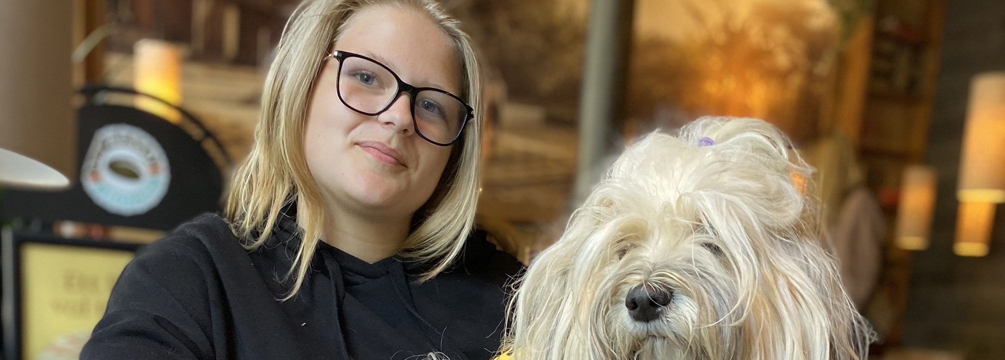 Julia sitter i en soffa med sin assistanshund Valkyria i knät. 