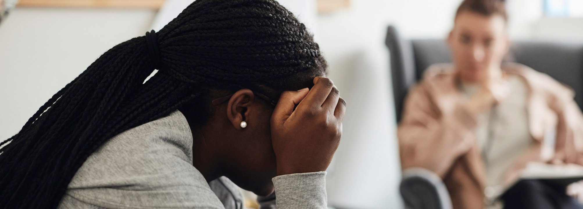 Ledsen kvinna som gömmer ansiktet samtalar med en terapeut.