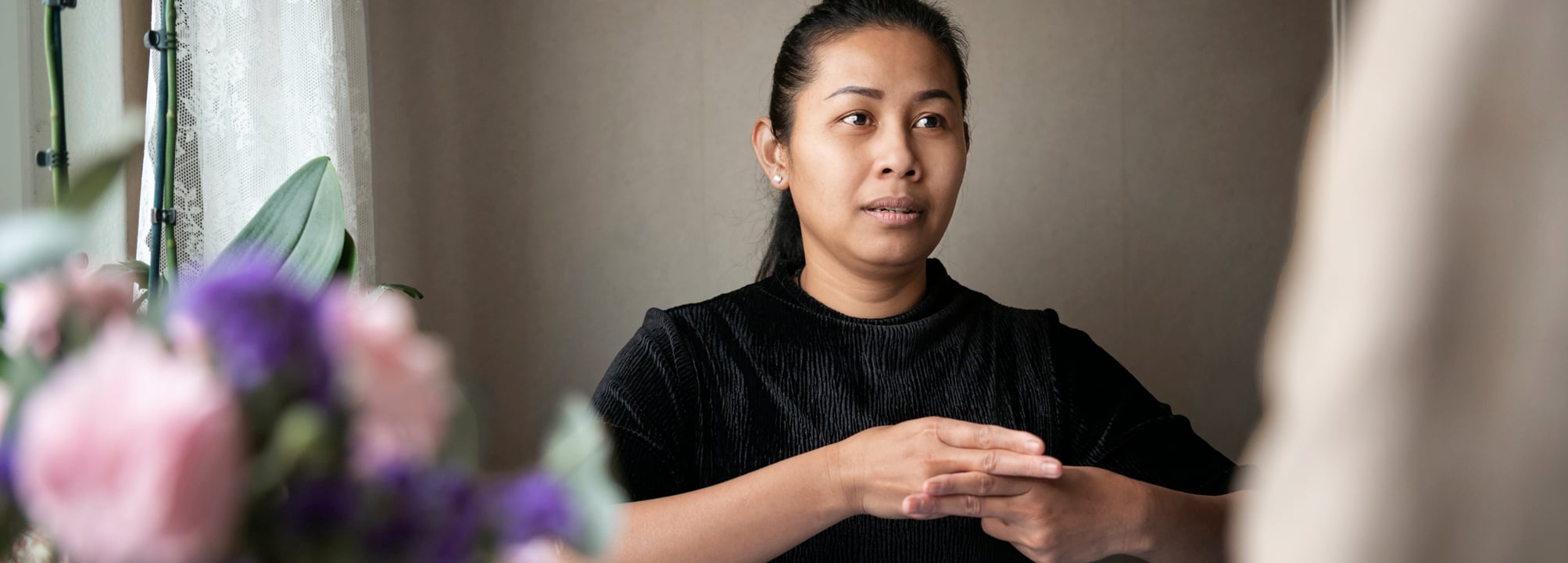Kvinna talar med person på andra sidan av ett matbord.