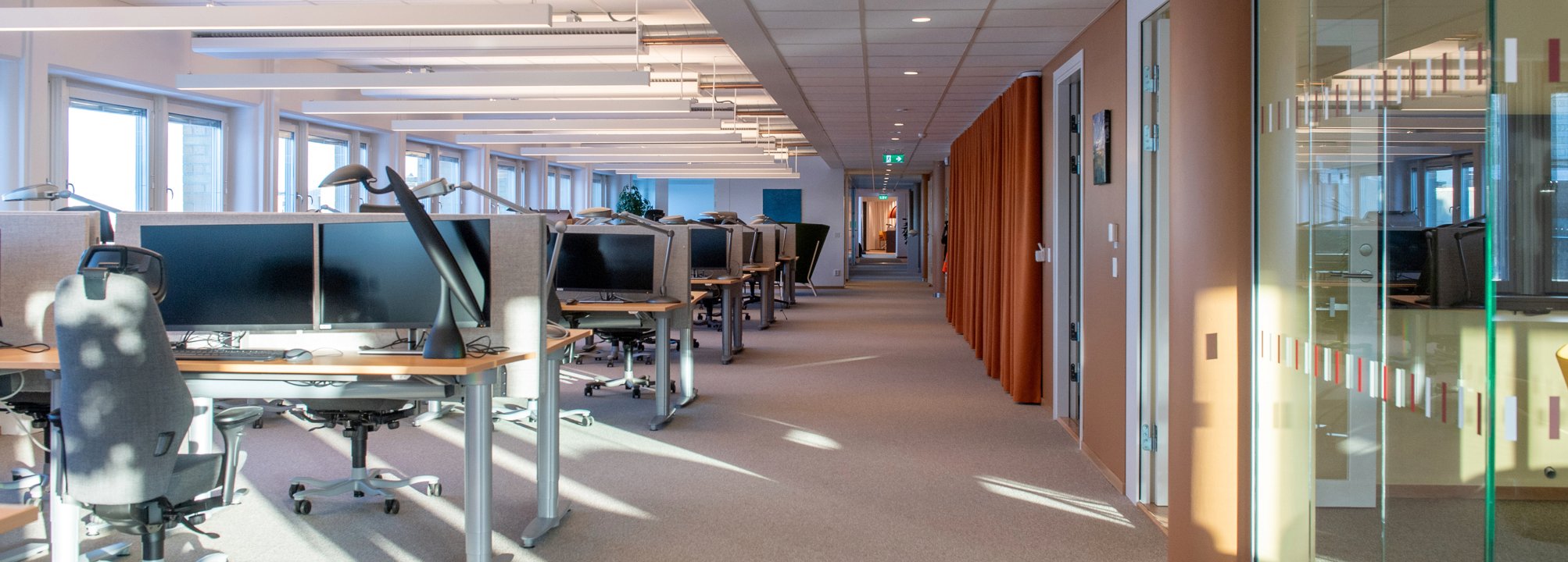 Vy från MFD:s kontor med flera skrivbord, stolar och ett inglasat mötesrum.